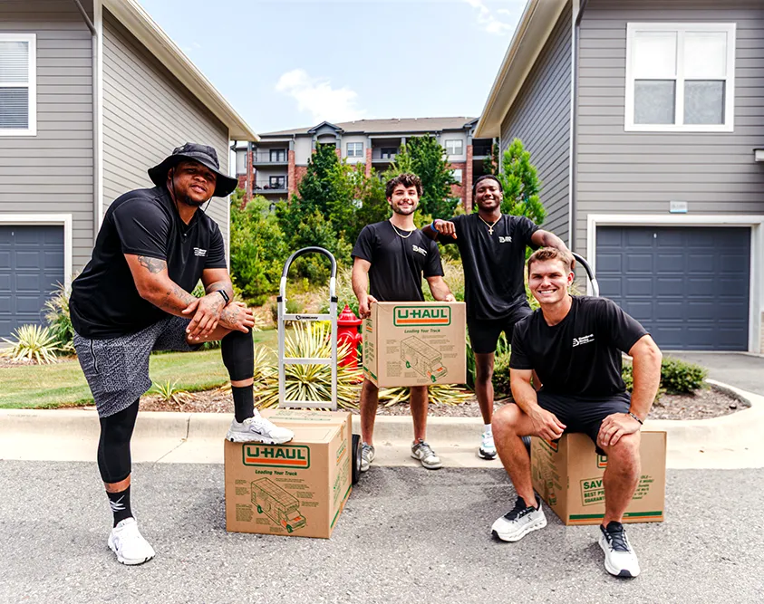 four young movers posing with boxes